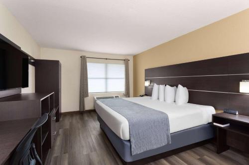 a hotel room with a bed and a flat screen tv at Baymont by Wyndham Punta Gorda/Port Charlotte in Punta Gorda