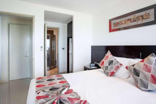 a bedroom with a white bed with red and black pillows at Ramada Suites by Wyndham Wailoaloa Beach Fiji in Nadi