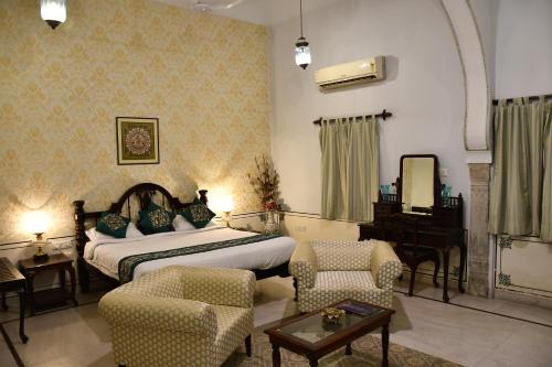 a bedroom with a bed and chairs and a piano at Khandela Haveli - a Boutique Heritage Hotel in Jaipur
