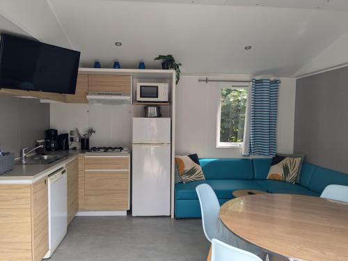 a kitchen and a living room with a blue couch at Cozy Tiny SolHouse 7 - Near Groningen - 5 Star Location in Kropswolde