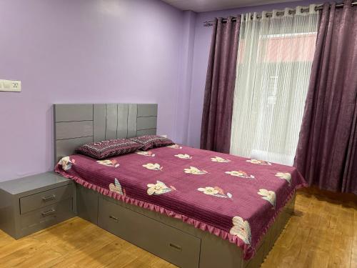a bedroom with a bed with a purple comforter and a window at Zen Cove in Kurseong