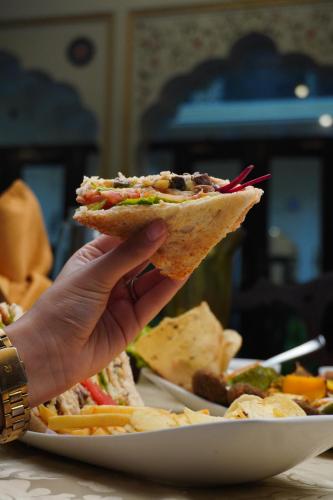 ジャイプールにあるKhandela Haveli - a Boutique Heritage Hotelの皿の上のサンドイッチのスライスを持っている人