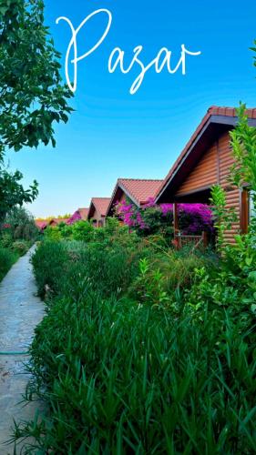 a house in a field of flowers next to a path at Leontopolis Apart Otel in Cıralı