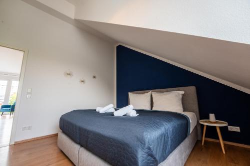 a bedroom with a bed with a blue wall at SCHLOSSBERG RESIDENCES - Design City-Apartment Nähe SAP und Hockenheimring in Hockenheim
