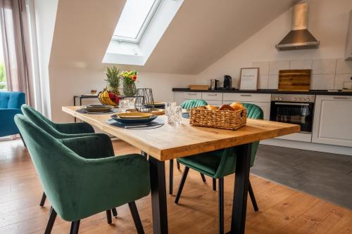 a kitchen with a wooden table and green chairs at SCHLOSSBERG RESIDENCES - Design City-Apartment Nähe SAP und Hockenheimring in Hockenheim
