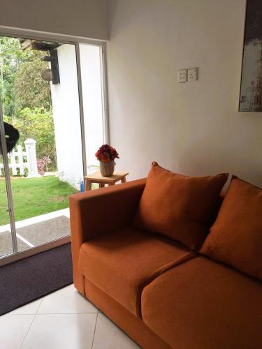 a brown couch in a living room with a window at Camellia Mountain Villa in Kiriwan Eliya