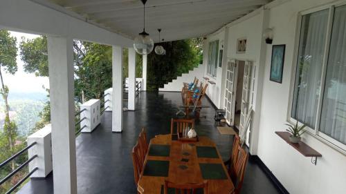 a porch with a table and chairs on a house at Camellia Mountain Villa in Kiriwan Eliya