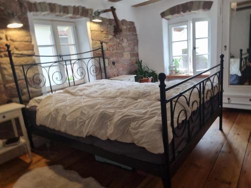 a black bed in a room with a brick wall at Nachtwächterhäuschen mit Sauna in Blieskastel