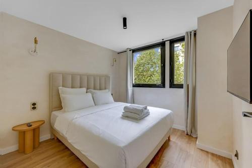 - une chambre blanche avec un grand lit blanc et 2 fenêtres dans l'établissement Splendide appartement à Avenue Achille Peretti II, à Neuilly-sur-Seine