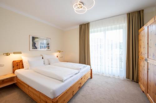 a bedroom with a large bed and a large window at Die WUNDER s Ferienpension in Pörtschach am Wörthersee