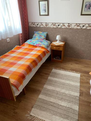 a bedroom with a bed and a table and a rug at Sára Vendégház Buzsák in Csisztapuszta