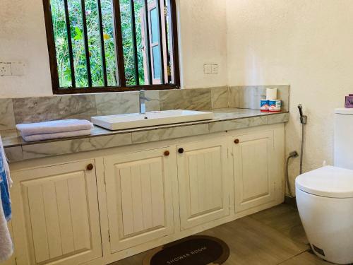 a bathroom with a sink and a toilet at Whispering House in Tangalle