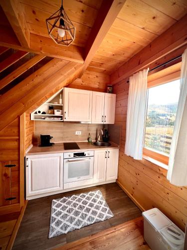 a kitchen with white cabinets in a wooden cabin at Starry Sky Zlatibor in Krajevi