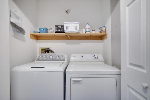 a small kitchen with two white washes and a shelf at 3 BR 2 BA Modern home with private hot tub, fire pit and lake view, Dogs ok! in Tobyhanna