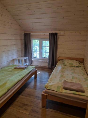 a room with two beds in a log cabin at Bona Natura Pirtelė in GratiÅ¡kÄ—s