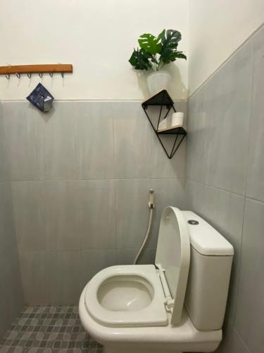 a bathroom with a toilet with a plant on the wall at Robiu Bed & Breakfast in Banyuwangi