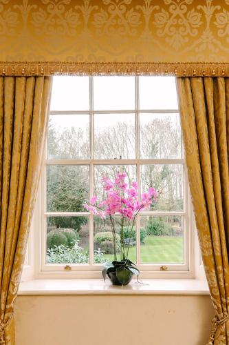 a vase with pink flowers sitting on a window sill at Ansty Hall in Coventry