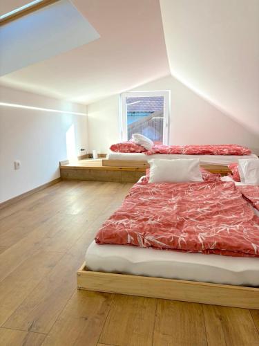 two beds in a room with wooden floors and a window at Tokaj Lamour in Tokaj