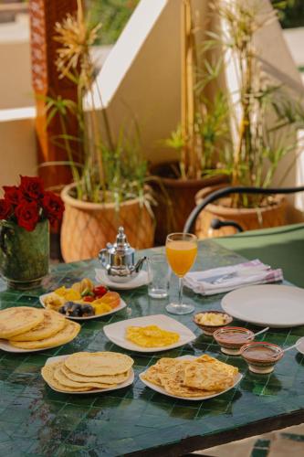 a table with plates of food and a glass of orange juice at Riad Senja in Marrakech