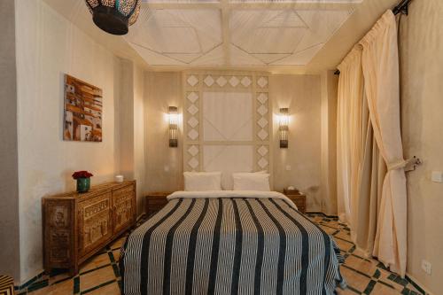 a bedroom with a bed with a black and white striped blanket at Riad Senja in Marrakech