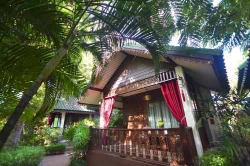 a house with a balcony and a palm tree at Thai Thai Sukhothai Resort in Sukhothai