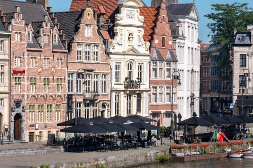 a group of buildings with tables and umbrellas at Ghent Marriott Hotel in Ghent