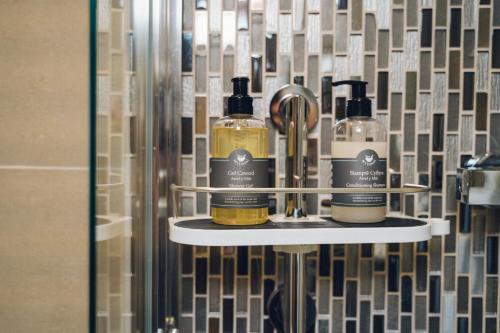 three bottles of alcohol on a shelf in a bathroom at The Manor Boutique Hotel Restaurant and Bar in Conwy