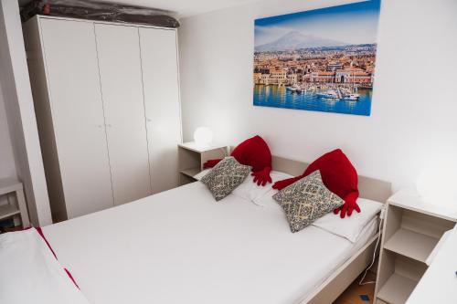 a bedroom with a white bed with red pillows at Perla Azzurra in Catania