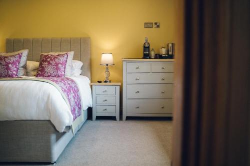 a bedroom with a bed and a dresser with a lamp at The Manor Boutique Hotel Restaurant and Bar in Conwy
