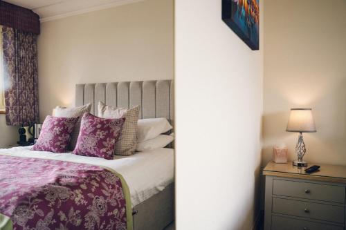 a bedroom with a bed with purple and white pillows at The Manor Boutique Hotel Restaurant and Bar in Conwy