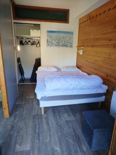 un lit dans une chambre avec un mur en bois dans l'établissement VALMEINIER 1800, à Valmeinier