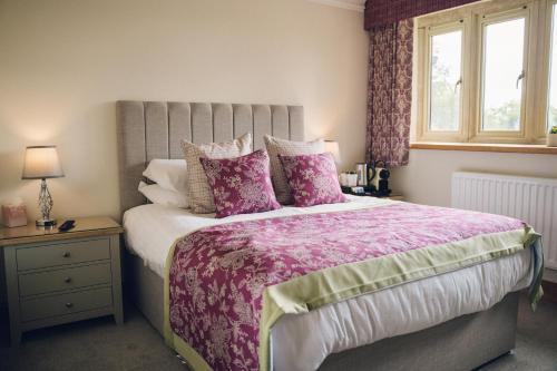 a bedroom with a large bed with pink sheets and pillows at The Manor Boutique Hotel Restaurant and Bar in Conwy
