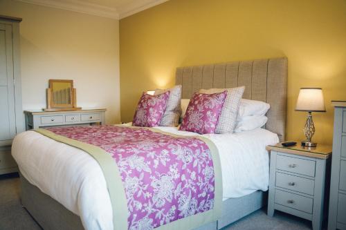 a bedroom with a large bed with pink pillows at The Manor Boutique Hotel Restaurant and Bar in Conwy