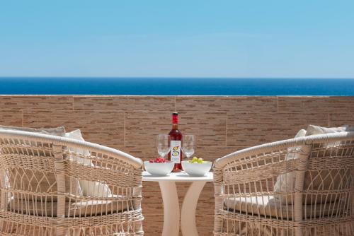 a table with a bottle of wine and two chairs at Splendor, piscina, junto a la playa, terraza privada con vistas al mar y preciosos atardecer in Puerto del Carmen