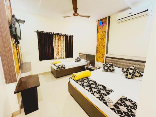 a hotel room with two beds and a television at Sai Balaji Residency in Shirdi