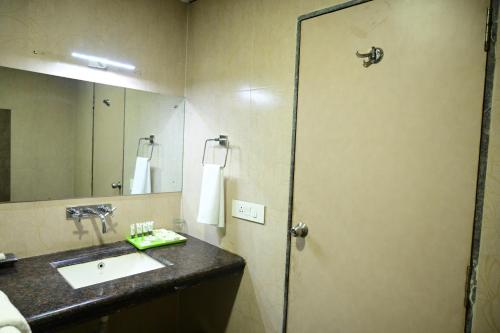 a bathroom with a sink and a large mirror at Pipul Utkal Continental in Jhārsuguda
