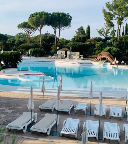 une piscine avec des chaises et des parasols en face de celle-ci dans l'établissement CAP Estérel FH007 , PISCINE CHAUFFÉE DU 05 avril au 02 Novembre , superbe parc aquatique ,Animations restaurants,boutiques, activités sportives village Club tout inclus, à Saint-Raphaël