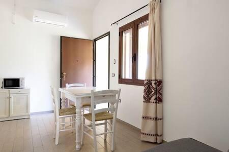 a dining room with a white table and chairs at Armandiola in Cardedu