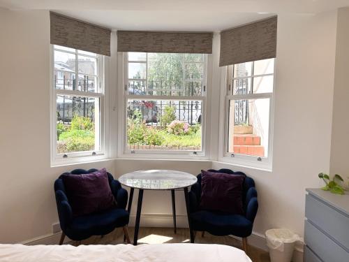 two chairs and a table in a room with windows at The Avonmore Olympia in London