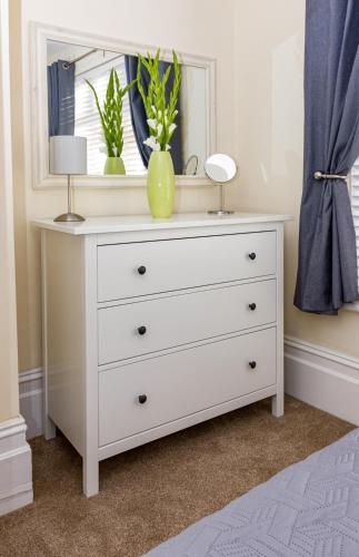 a white dresser with a mirror and two lamps on it at Prince Apartments in Fareham