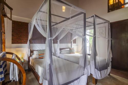 a bedroom with two beds and a canopy bed at Lion's Rest in Weligama