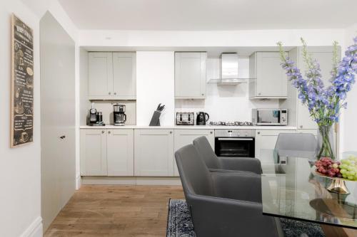 a kitchen with white cabinets and a glass table at PHENOMENAL OXFORD STREET 5bedroom DESIGN HOUSE NOMADS XXL GROUPS LOVE IT! in London