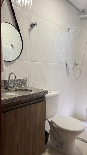 a bathroom with a toilet and a sink and a mirror at Zaffir Apartamento in Cuiabá