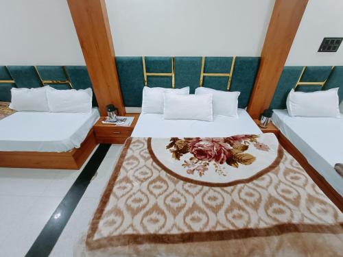 a hotel room with two beds and a plate of flowers at Hotel Shreem in Ujjain