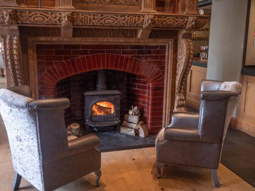 a fireplace with two chairs in front of a brick fireplace at The Manor Boutique Hotel Restaurant and Bar in Conwy