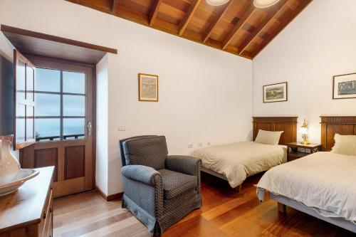 ein Schlafzimmer mit zwei Betten, einem Stuhl und einem Fenster in der Unterkunft Casa Rural La Era in Valverde