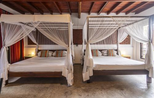 a bedroom with two beds with mosquito nets at Lion's Rest in Weligama