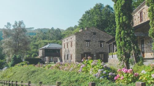 an old stone building with flowers in front of it at Aldea Rural y Gastro Restaurante Casona de Labrada in Labrada