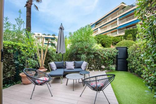une terrasse avec un canapé, des chaises et un parasol dans l'établissement RARE! 2-Br with Pools Beach Access Private Parking, à Cannes
