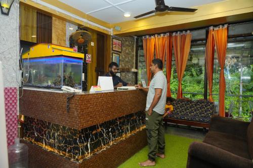 a man standing at a counter with a fish tank at Sea Pearl Homestay in Port Blair